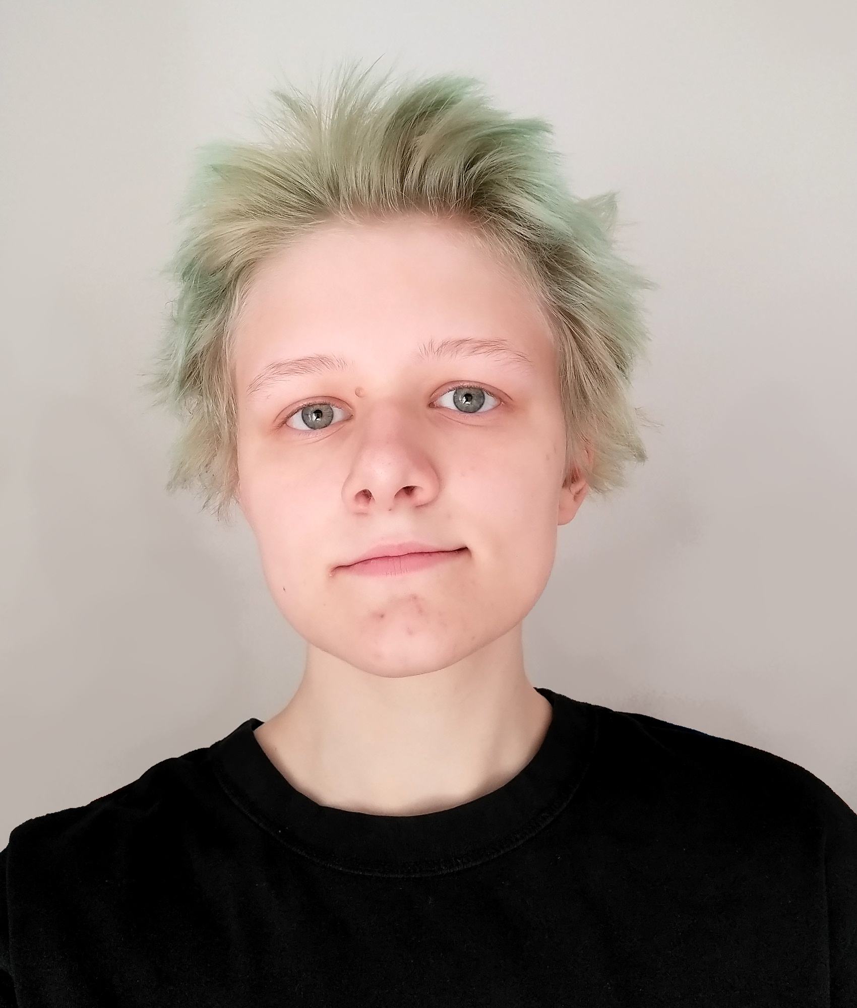 A photo of a young man with dyed greenish hair